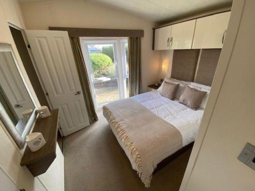 a small bedroom with a bed and a window at Beautiful Caravan With Decking At California Cliffs In Scratby Ref 50052l in Great Yarmouth
