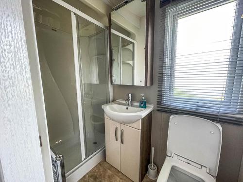 a bathroom with a toilet and a sink and a shower at Beautiful Caravan With Decking At California Cliffs In Scratby Ref 50052l in Great Yarmouth