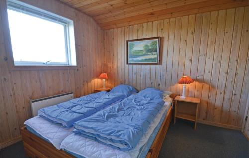 a bedroom with a bed with blue sheets and a window at 5 Bedroom Stunning Home In ster Assels in Ljørslev
