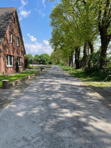 an empty road next to a barn and trees at Herbstleuchten im Hasetal, Becksvoort-Noll in Löningen
