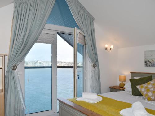 a bedroom with a large window with a view of the water at Kings Haven in Turnchapel