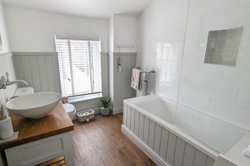 a white bathroom with a tub and a sink and a tub at Stunning Victorian Terrace in the Golden Triangle in Norwich