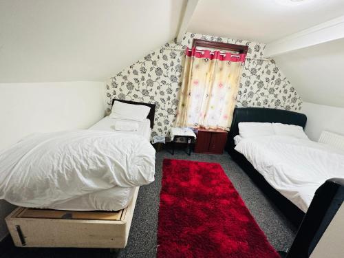 a bedroom with two beds and a red rug at Unique private rooms (1) in Bolton