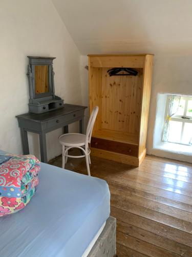 een slaapkamer met een bed, een bureau en een stoel bij Westland Traditional Cottage dated 1700's in Ardea