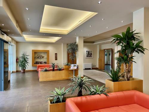 un vestíbulo de oficina con sofás naranjas y macetas en Hotel Ristorante Trendy, en Prato