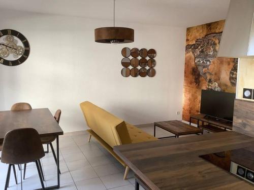ein Wohnzimmer mit einem Tisch, Stühlen und einer Uhr in der Unterkunft Très Joli T2 46 m2, Terrasse 32 m2, proche Remparts Avignon in Avignon