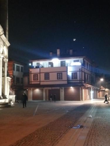 un edificio de noche con gente caminando delante de él en ESER PALAS OTELİ en Konya