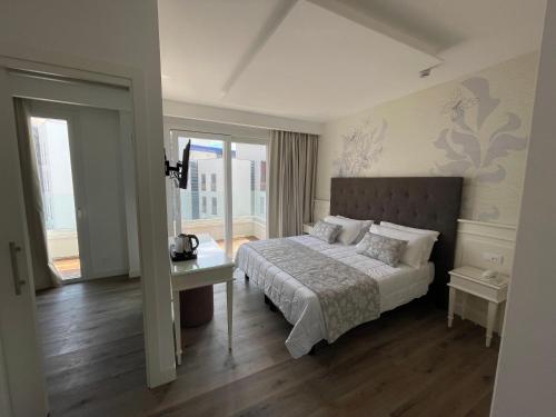 a bedroom with a bed and a table and windows at Park Hotel Cellini in Lido di Jesolo