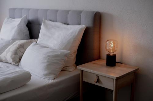 ein Bett mit weißen Kissen und einer Lampe auf dem Tisch in der Unterkunft Ferienhaus am Mühlenweiher 3 in Leutkirch im Allgäu