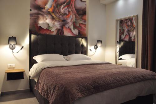 a bedroom with a large bed with a painting on the wall at In&Out in Nafplio