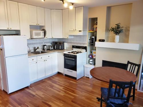 cocina con electrodomésticos blancos y suelo de madera en Bright Garden Suite by the Beach and UBC en Vancouver
