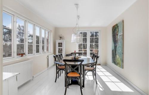 a dining room with a table and chairs and windows at Cozy Apartment In Gudhjem With Kitchen in Gudhjem