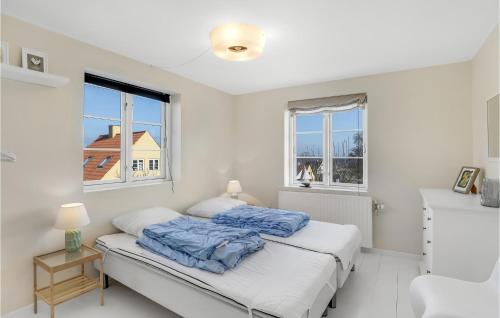 a white bedroom with a bed and two windows at Cozy Apartment In Gudhjem With Kitchen in Gudhjem