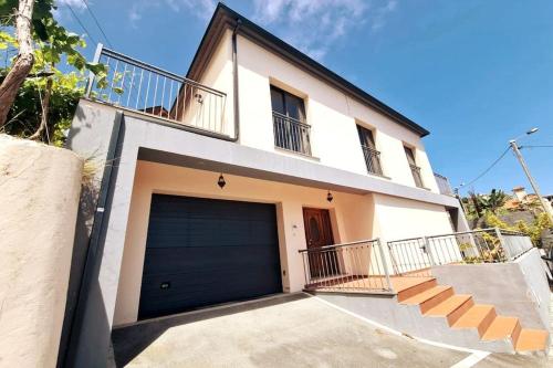 a white house with a garage door and stairs at Casa da Portada in Seixal