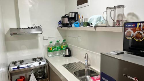 kuchnia ze zlewem, kuchenką i butelkami wody mineralnej w obiekcie Jannah’pad w mieście Manila