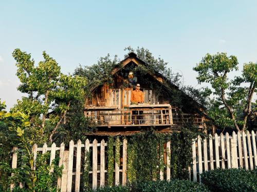 a man standing on the balcony of a tree house at Tiệm Cà Phê Mer Homestay & Coffee Mộc Châu in Mộc Châu