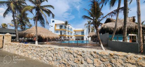 un complejo con piscina y palmeras en Sereni San Bernardo Hotel Playa, en San Bernardo del Viento
