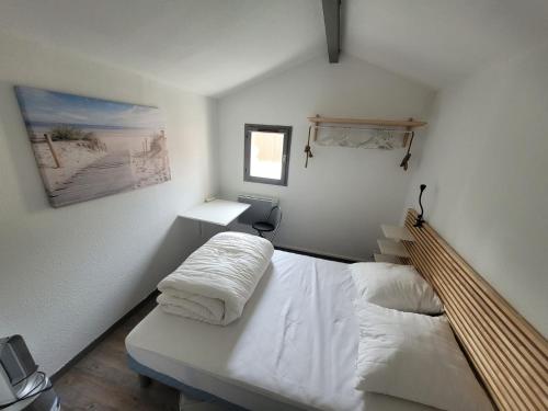 une chambre avec un lit avec des draps blancs et une fenêtre dans l'établissement Maison tout confort à la mer 200m de la plage, 2 chambres, 2min Royan, à Saint-Georges-de-Didonne