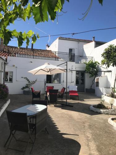 uma mesa e cadeiras com um guarda-sol em frente a uma casa em Casa Santo Antonio em Pias