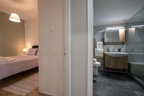 a bedroom with a bed and a bathroom with a sink at Anesis with a Yard in Kalamata