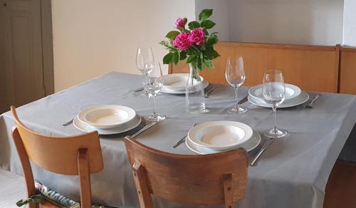 una mesa con platos y vasos y un jarrón de flores en Cò d'Franz - PT, en Ponto Valentino