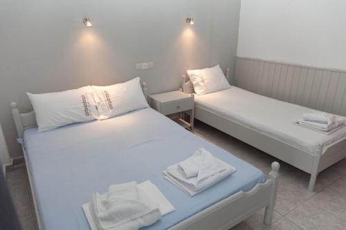 two beds in a small room with white sheets at Villa Veneti in Néos Pírgos