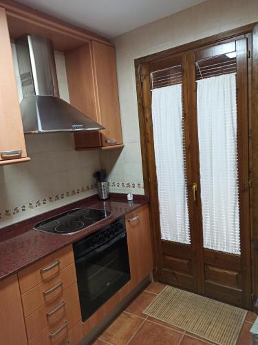 uma cozinha com armários de madeira e um forno com placa de fogão em Apartamento rural Ca La Rumbeta en La Fresneda em La Fresneda