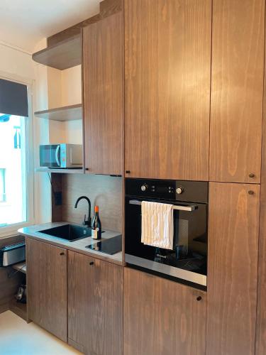 La cuisine est équipée de placards en bois, d'un évier et d'un four. dans l'établissement Appartement charmant centre Biarritz, à Biarritz