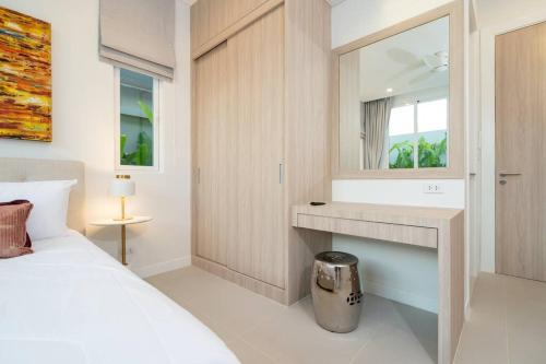a bedroom with a white bed and a mirror at Peykaa Estate Pool Villa by HCR in Phuket Town