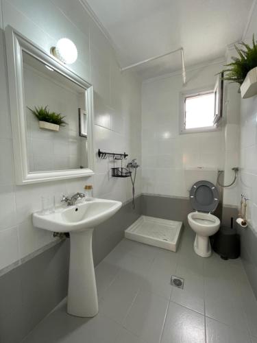 a white bathroom with a sink and a toilet at Palatino in Afitos