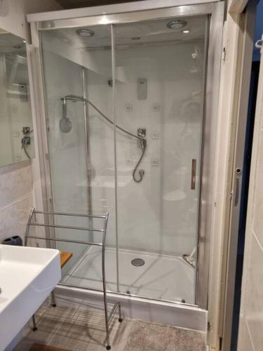 une douche avec une porte vitrée dans une salle de bain dans l'établissement appartement en rez de jardin, à Foce