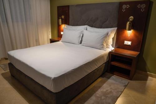 ein Schlafzimmer mit einem großen Bett mit weißer Bettwäsche und Kissen in der Unterkunft Résidence hôtelière & Resort - Moroccan Floors in Tangier