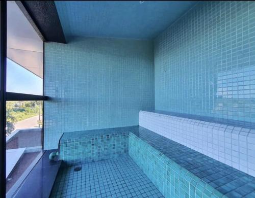 a blue tiled bathroom with a tub and a window at BHF》1107•Conforto e tranquilidade. Flat beira mar! in Recife