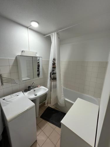 - une petite salle de bains blanche pourvue d'un lavabo et d'une baignoire dans l'établissement Séte 6eme vue sur le canal et l'étang, à Sète