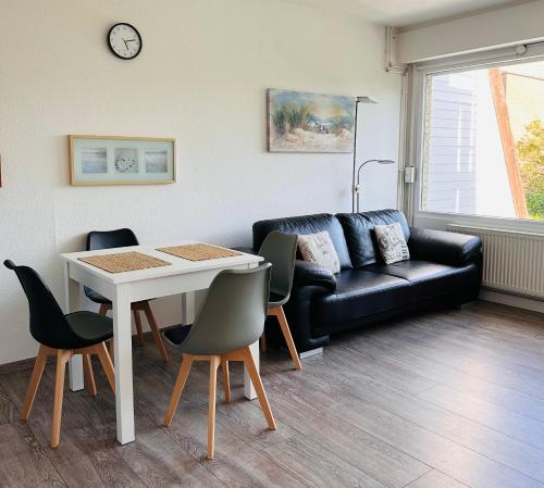 a living room with a couch and a table and chairs at FeWo Seeluft - Hooksiel in Wangerland