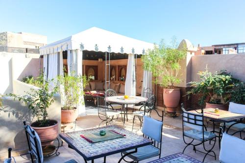 an outdoor patio with tables and chairs and plants at RIAD KECHMARA in Marrakesh