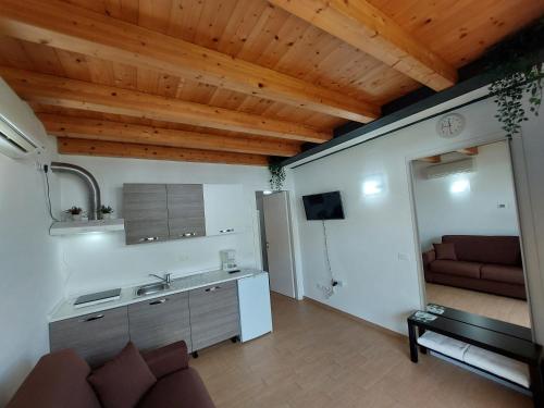 a kitchen and living room with wooden ceilings and a couch at Pizzocolo resort fasano in Gardone Riviera