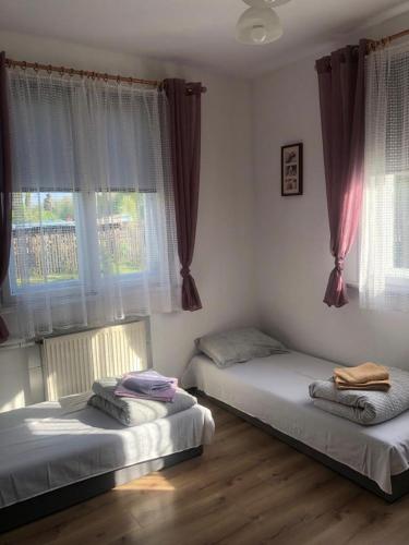 two beds sitting in a room with windows at Dom pod lasem in Ruciane-Nida