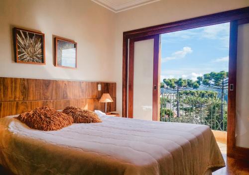 a bedroom with a large bed with a large window at Pousada Victoria Villa By Nacional Inn in Campos do Jordão