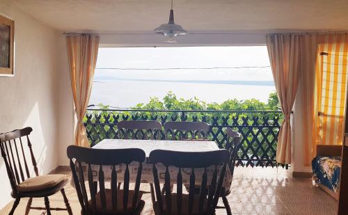 a dining room with a table and chairs and a balcony at Apartmani Košutić in Stara Baška
