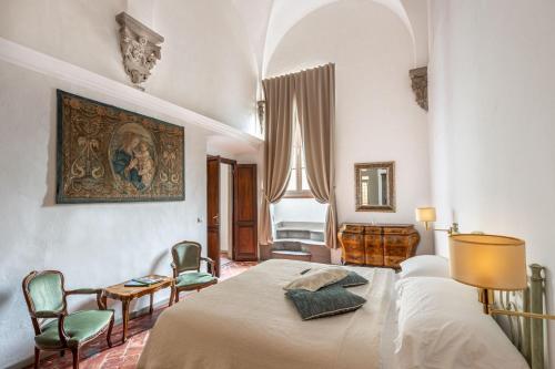 1 dormitorio con 1 cama, sillas y una pintura en la pared en Palazzo Roselli Cecconi Apartments, en Florencia