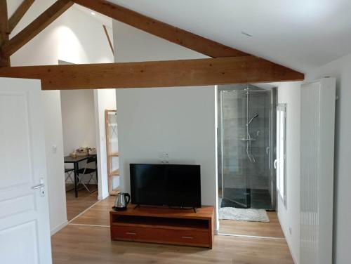 ein Wohnzimmer mit einem Flachbild-TV auf einem Holztisch in der Unterkunft Chambre d'hôtes dans maison charentaise in Mortiers
