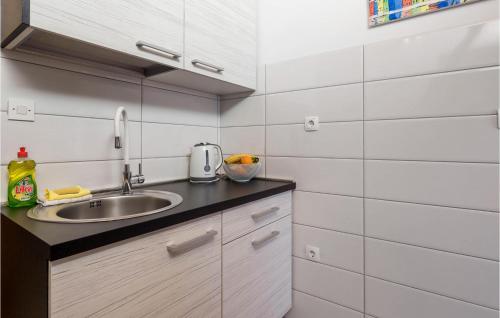 una pequeña cocina con fregadero y azulejos blancos en Cozy Apartment In Lovran With Wifi, en Lovran