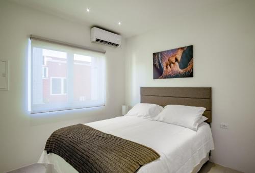 a bedroom with a large white bed with a window at Trankilidad Apartments in Santa Cruz