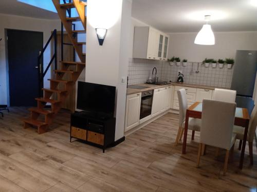 cocina y sala de estar con TV y escalera en Niedźwiady Małe 14 B, en Ślesin