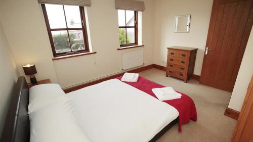 a bedroom with two beds and a dresser and windows at Barcud Lodge, Llangennith in Llangennith