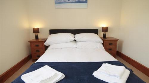 a bedroom with a bed with white sheets and pillows at Barcud Lodge, Llangennith in Llangennith