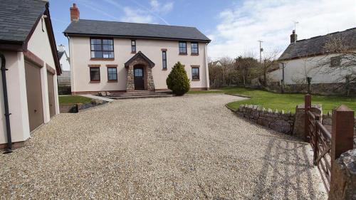 a large white house with a gravel driveway at Barcud Lodge, Llangennith in Llangennith