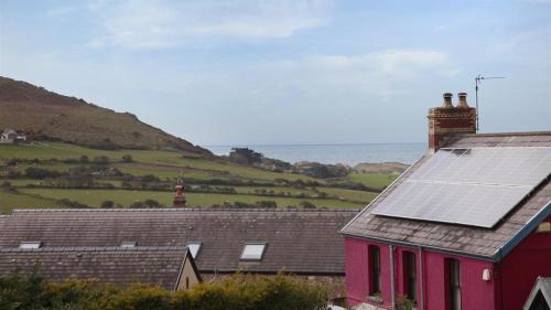 a red house with a solar panel on the roof at Barcud Lodge, Llangennith in Llangennith