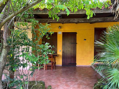 a yellow house with a wooden door and a patio at Sa Mola in Bonarcado